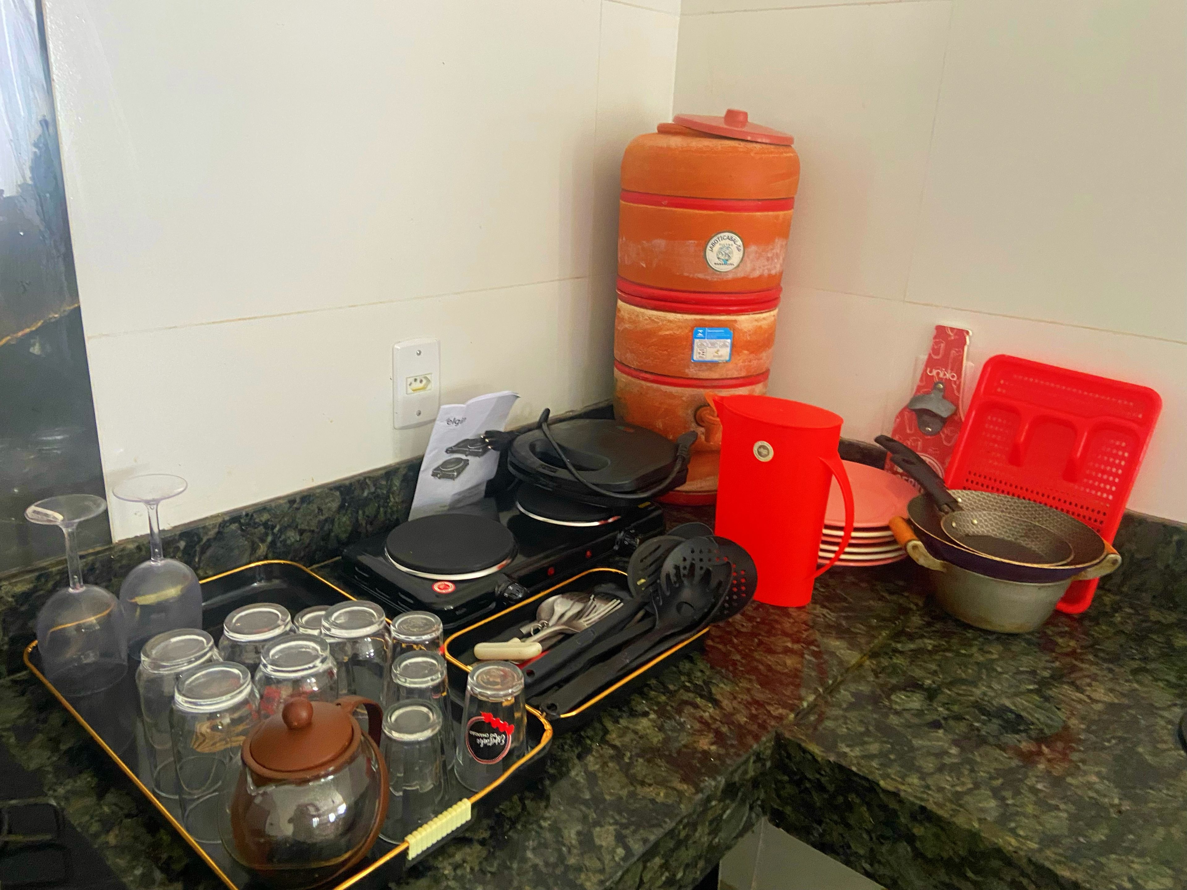 Una encimera de cocina con diferentes utensilios de cocina, una tetera y recipientes de almacenamiento.