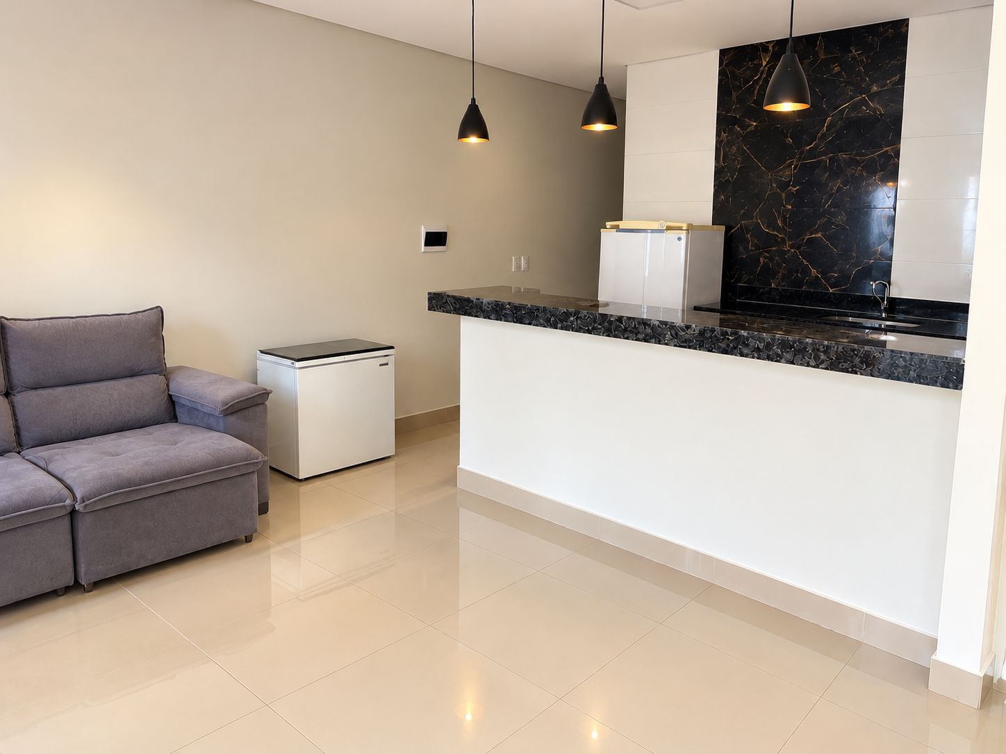 Una cocina moderna con salpicadero de mármol, refrigerador empotrado e iluminación colgante.