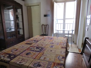 Ein Zimmer mit einem Bett, einem Holzschrank, einem Stuhl, einem Balkon und einer Tür.