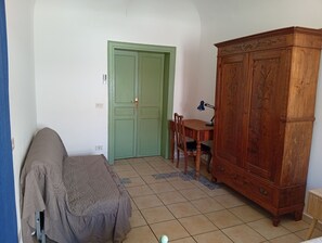 A room with a green door, a wooden cabinet, a desk with a chair, and a bed with a blanket. - New Listing (Palermo)