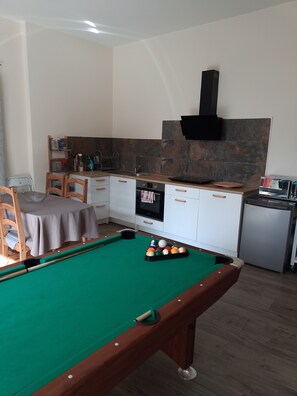 A pool table with balls, a dining area with a table and chairs, a kitchen with a stove and sink, and a small refrigerator. - New Listing (Lansargues)