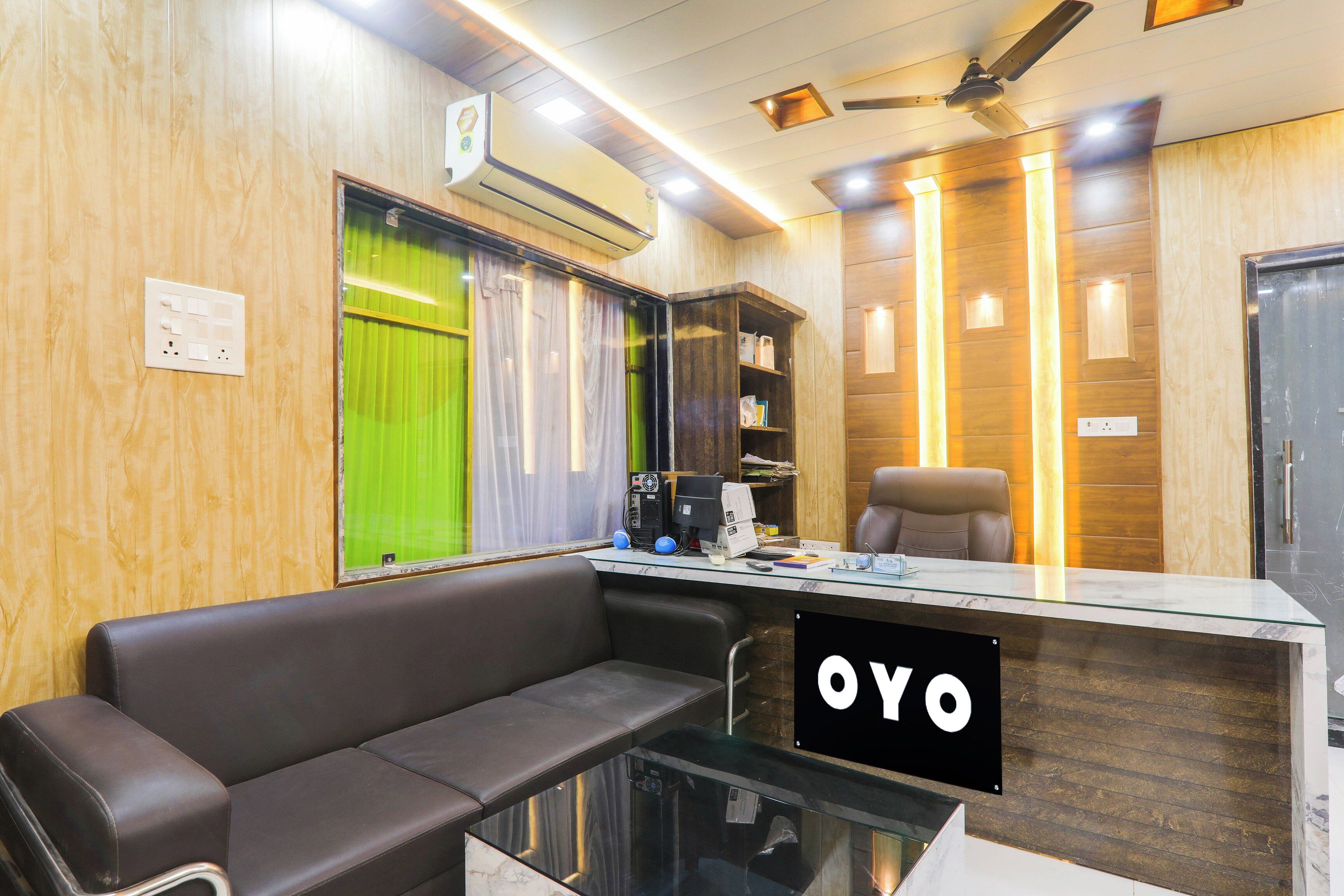 Un área de recepción con un sofá, un escritorio con cubierta de vidrio y un letrero que dice 'OYO'.