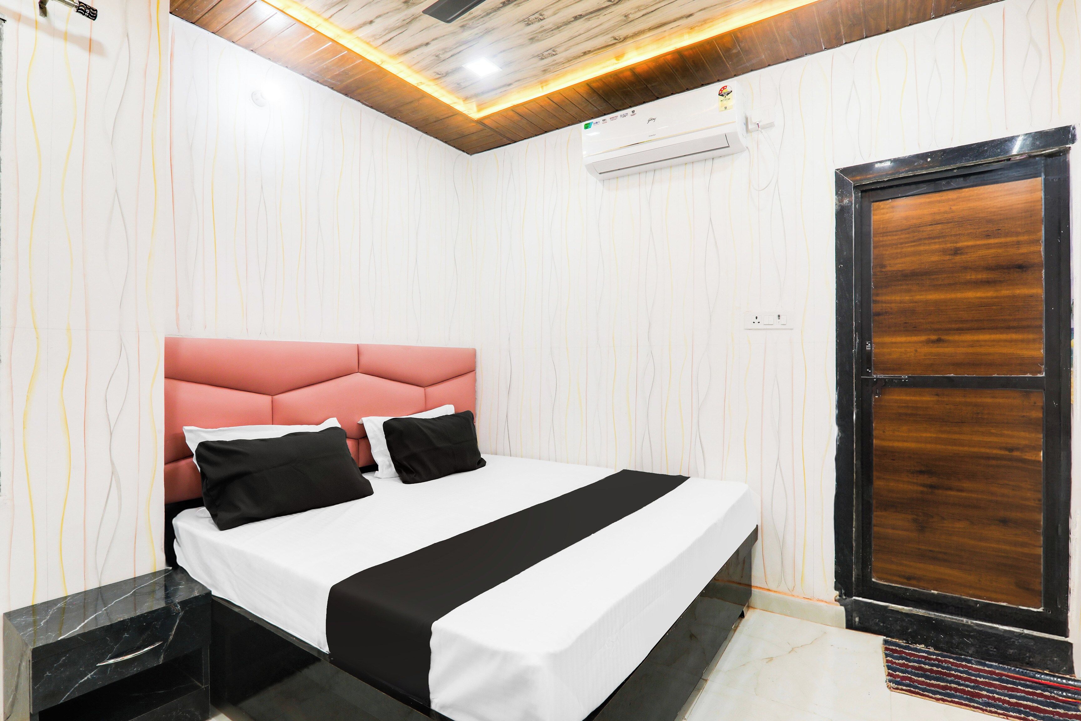 Una habitación de hotel con una cama, una puerta de madera y un piso de mármol.