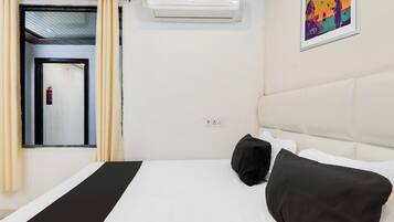 Habitación de hotel con una cama, una ventana con cortinas, un equipo de aire acondicionado y un cuadro en la pared.