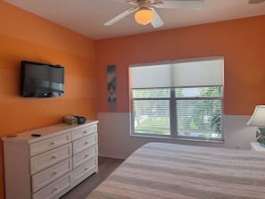 A bedroom with a bed, a dresser, a television, a window with blinds, and a ceiling fan. - Siesta Key | Pool, Spa & Flexible 1-2 Bedroom Lock-Off (Siesta Key)