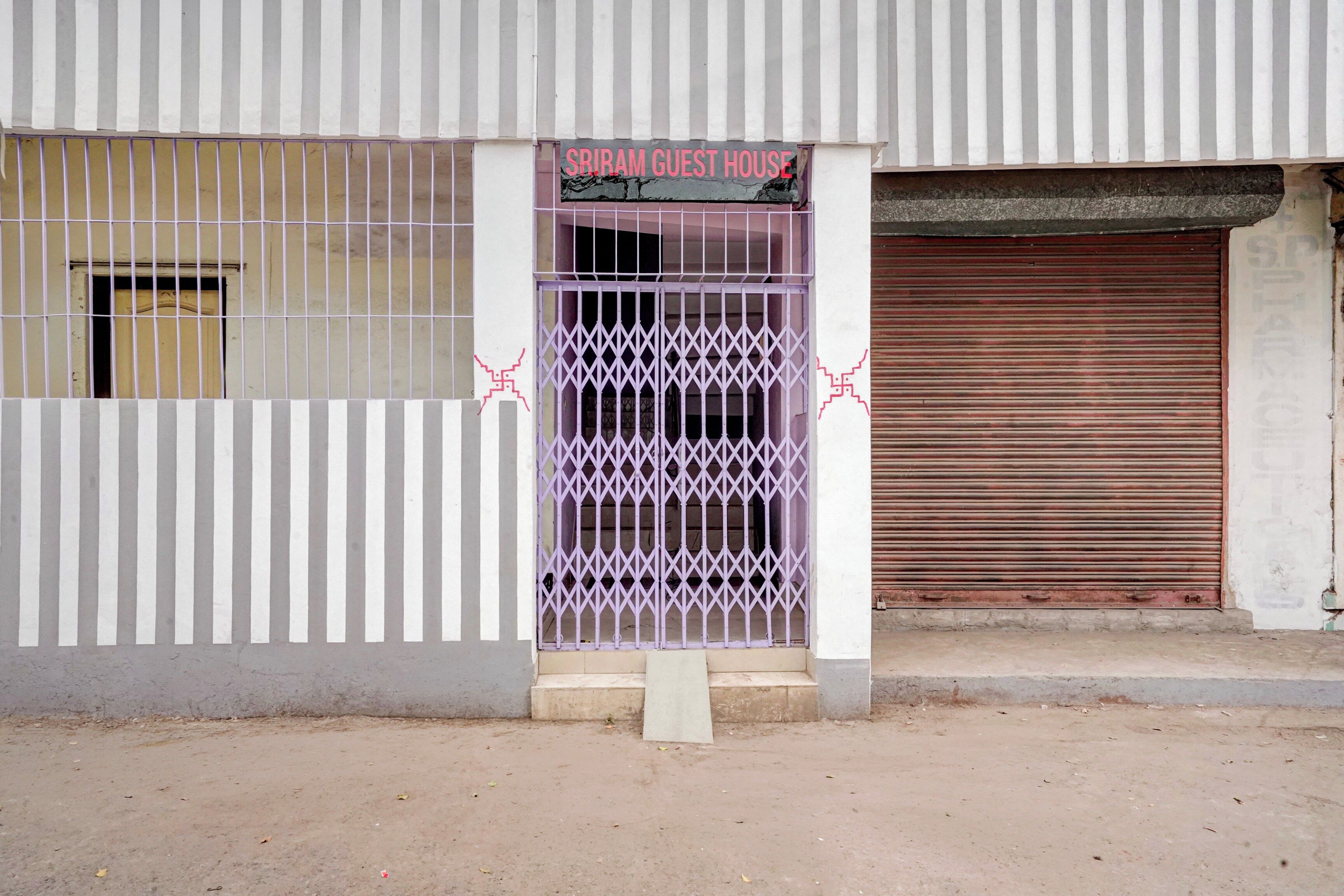 A building with a sign reading 'SRIRAM GUEST HOUSE' above a gated entrance.