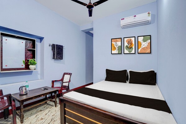 A bedroom with a bed, a desk, a chair, a potted plant, and wall art. - Hotel O Sri Ram Guest House (Kendrapara)