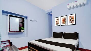 Un dormitorio con una cama, una ventana, aire acondicionado instalado en la pared y cuadros enmarcados.
