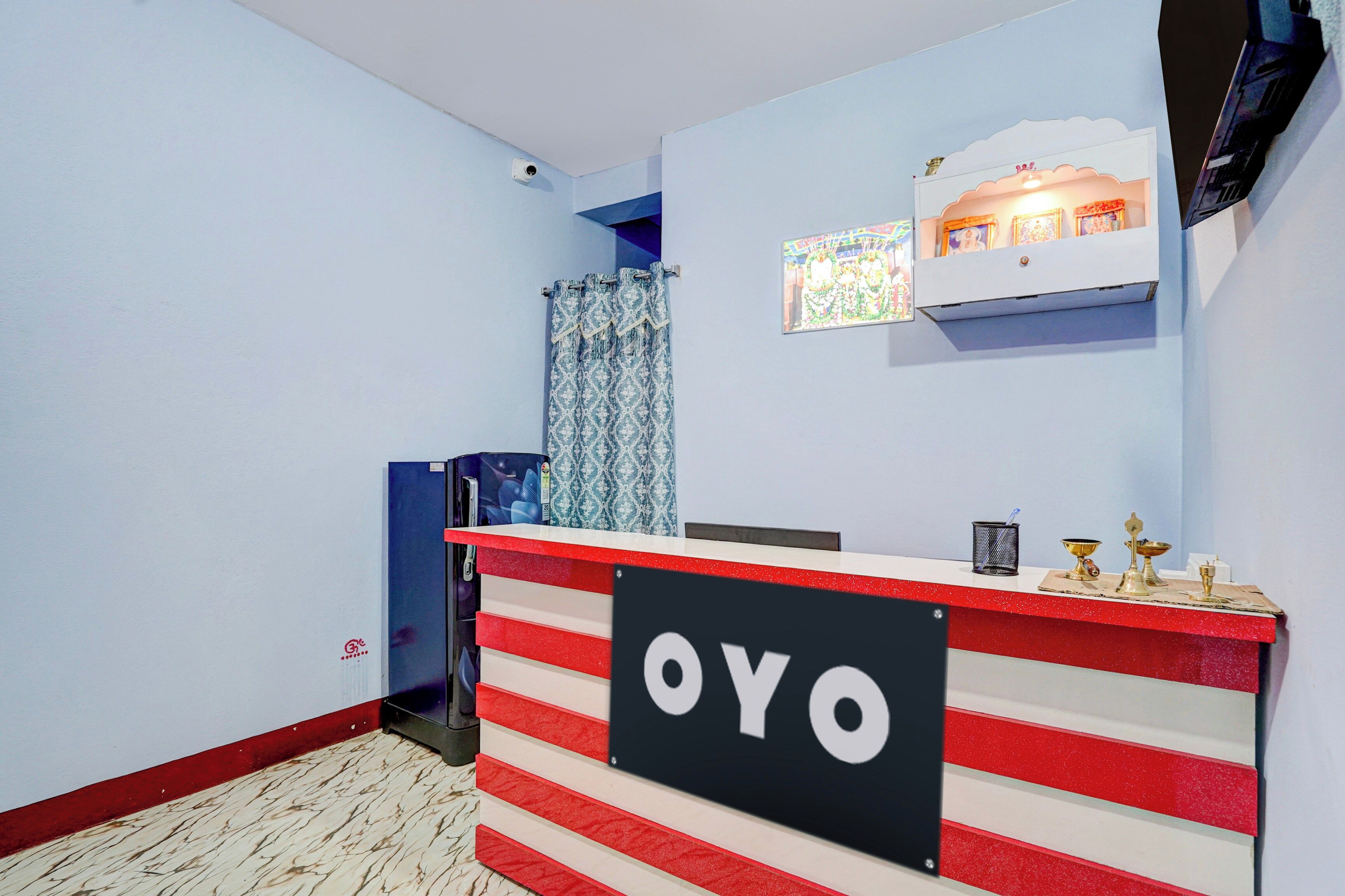 Una recepción con un letrero que dice 'OYO' y un pequeño santuario con objetos religiosos encima.
