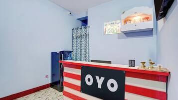 Una recepción con un letrero que dice 'OYO' y un pequeño santuario con objetos religiosos encima.