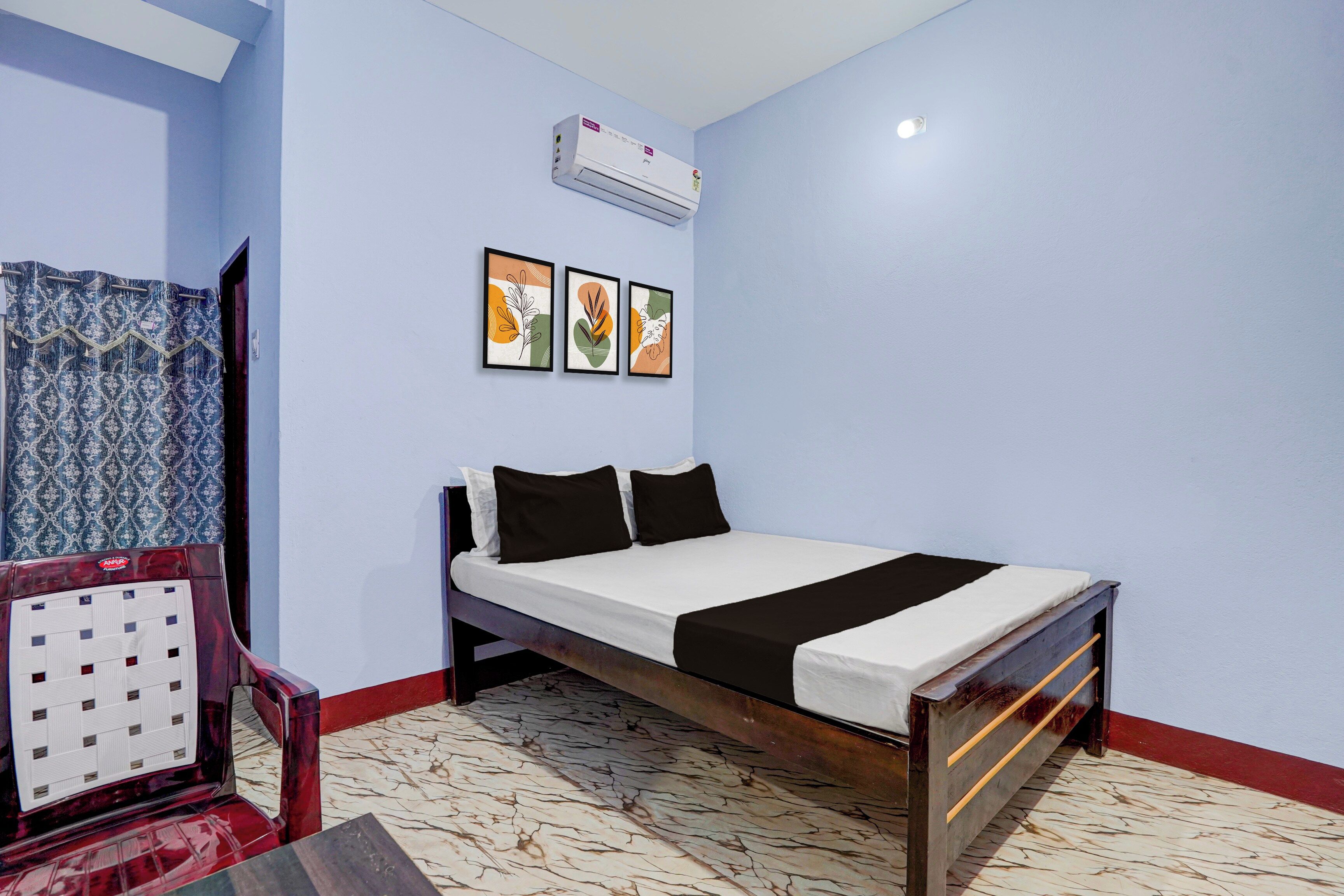 Un dormitorio con una cama, un aire acondicionado de pared y tres obras de arte enmarcadas.