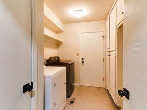 A laundry room with a washing machine, dryer, and stacked cabinets. - Spacious 6-bedroom house in serene Tulsa with cool AC (Tulsa)
