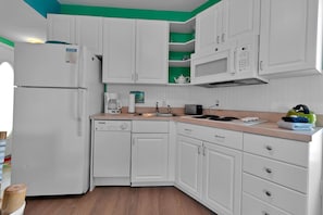 A compact kitchen with white cabinets, a built-in microwave, a coffee maker, and a kettle on the countertop. - Siesta Key Lock-Off: Studio + 2BR, Pool & Walk to Beach & Village (Siesta Key)