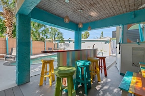 A covered outdoor area with a pool, colorful stools, and a bar. - Studio + 2BR Lock-Off | Pool, Walk to Beach & Siesta Village (Siesta Key)