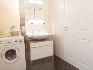 Ein modernes Badezimmer mit Waschmaschine, Waschbecken und Spiegel.