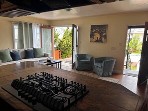 Ein Wohnzimmer mit einer Gaskochstelle, einem Sofa, zwei Sesseln und einem Gemälde an der Wand.