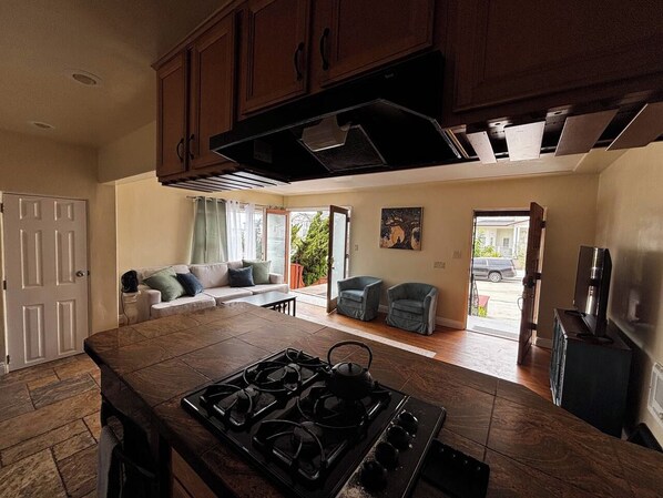 A kitchen with a central island, wooden cabinets, and a dining area with a sofa and chairs. - La Jolla Coastal Retreat Walk to the Beach, Dining and Designated Parking (San Diego)