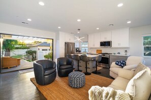 A modern kitchen with white cabinets, a stainless steel refrigerator, and a microwave. - Bright Coastal 2BR Home • Huge Yard • Walkable • 10 Mins To The Beach (Los Angeles)