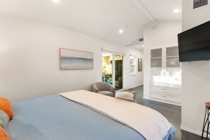 Un dormitorio con cama, una silla, armario y un cuadro en la pared.