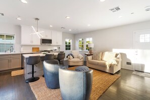 A modern kitchen with white cabinets, a microwave, and a dining area with bar stools. - Bright Coastal 2BR Home • Huge Yard • Walkable • 10 Mins To The Beach (Los Angeles)