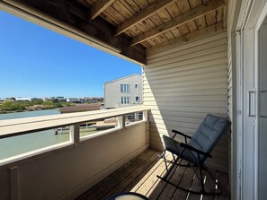 A balcony with a view of a river and houses, a chair, and a door. - Waterfront Port Isabel/South Padre Condo for long term rent!! Sleeps 6 (Port Isabel)