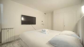 Een hotelkamer met een bed, een aan de muur bevestigde televisie, een radiator en een deur.