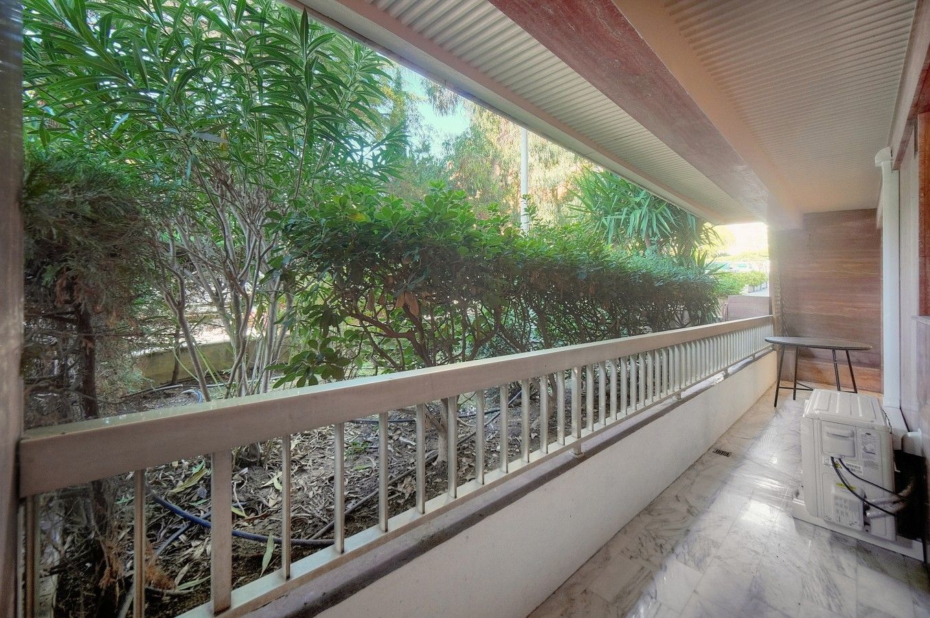 A balcony with a metal railing, a small table, and a chair.