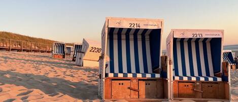 Sillas de playa con los números 2214 y 2213 en una playa arenosa.