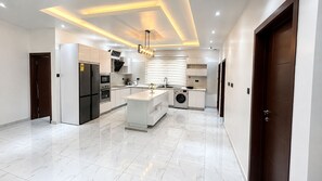 A modern kitchen with a central island, built-in appliances, and recessed lighting. - ThePeppy Apartment (Prampram)