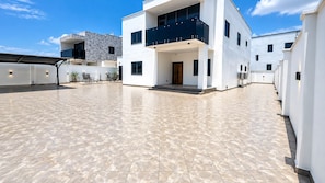 A modern building with a spacious courtyard, a covered outdoor seating area, and a pool. - ThePeppy Apartment (Prampram)