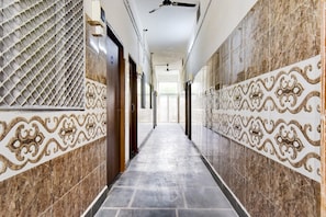 A hallway with patterned walls, a tiled floor, and doors leading to rooms.