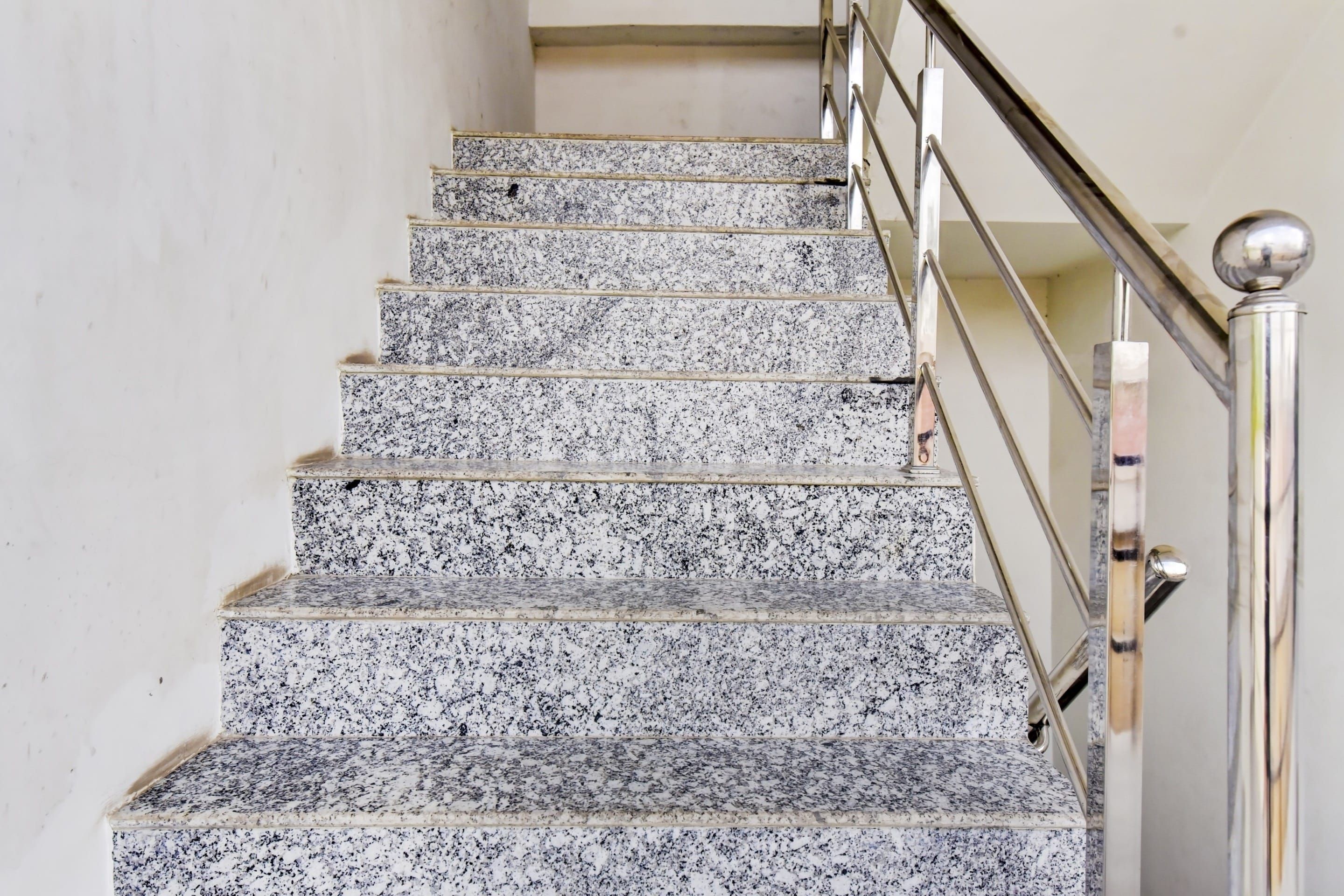 Una escalera con escalones de granito y barandilla de metal.