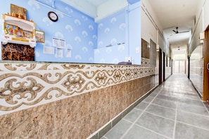 Zona d'arrencada d'hotel amb mostrador de marbre, parets de paper blau i un paviment de rajoles.