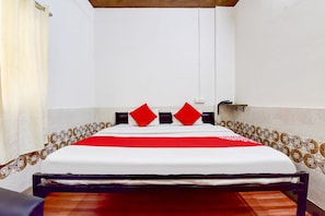 Un llit amb matalàs blanc, almoines vermelles i negres i un edredó vermell en una habitació amb parets de disseny i terra de fusta.
