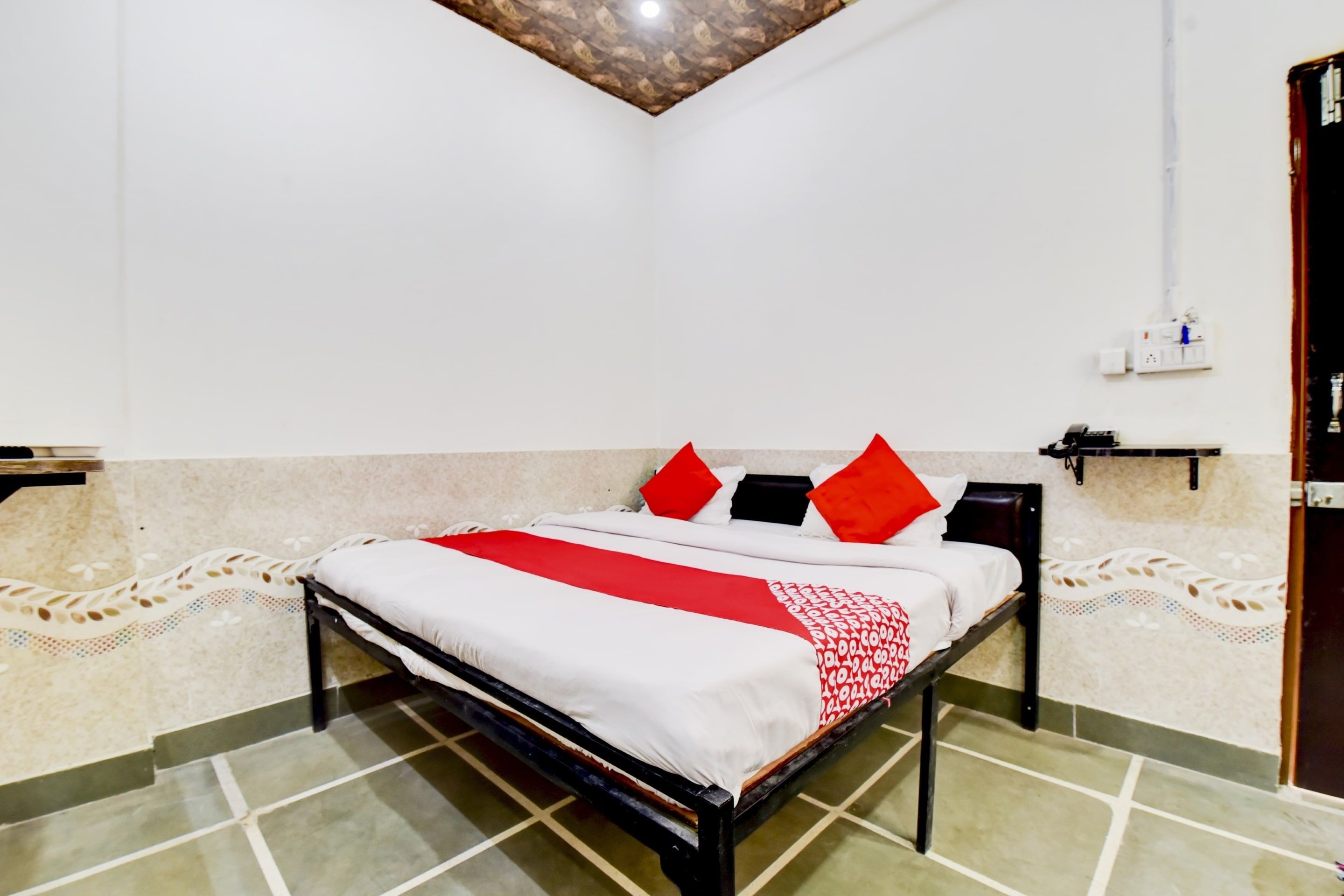 Un dormitorio con cama, mesita de noche y enchufe en la pared.