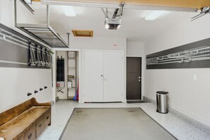 A clean, well-lit garage with a door, a bench, and a trash can. - Deer Valley Ski Retreat | Hot Tub & Fire Pit 1111 (Park city)