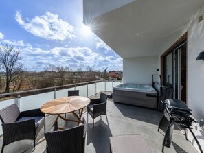 Ein Balkon mit Whirlpool, Gartenmöbeln und Blick auf die Landschaft.