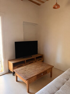 Ein Wohnzimmer mit einem Holz-TV-Schrank, einem Flachbildfernseher, einem Holztisch und einem Sofa.