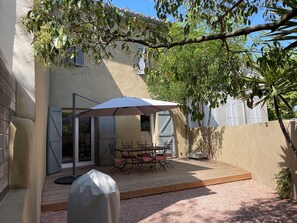 Eine Terrasse im Freien mit überdachtem Tisch und Stühlen, einem Grill und einer überdachten Sitzgruppe.