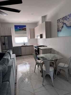 A modern kitchen with a dining area, a sofa, and a painting on the wall. - Aruban Charm | Private Pool | Seroe Janchi (Noord)