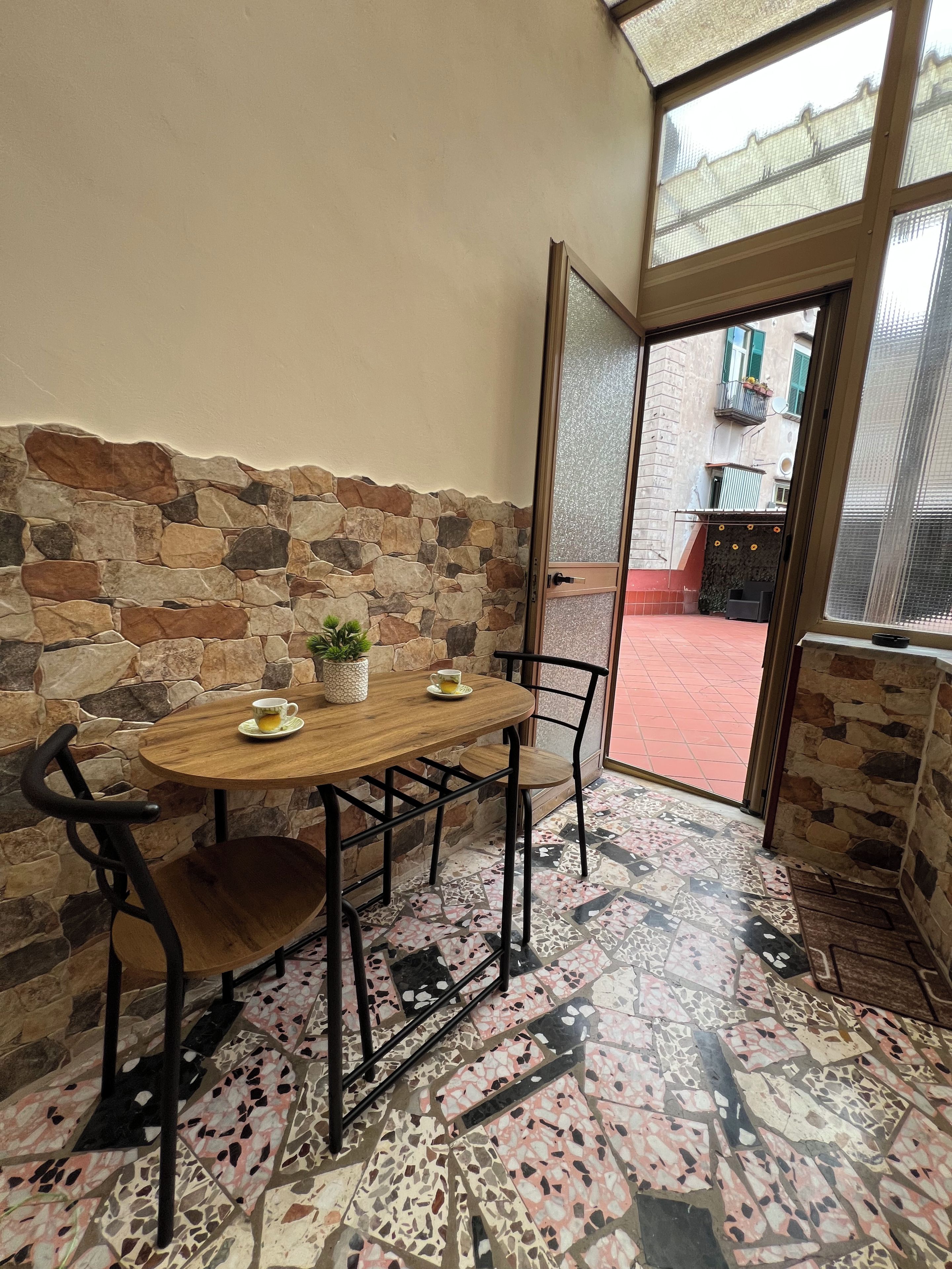 A cozy dining area with a stone wall, a wooden table, and metal chairs.