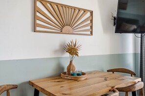 A wooden dining table with chairs, a wall-mounted TV, and a decorative wooden panel above the table. - 108 Latitude Adjustment (Murrells Inlet)