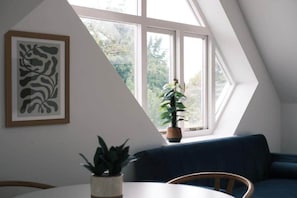 A room with a dining table, chairs, a blue sofa, a potted plant, and a framed artwork on the wall. - Flat 19A Blandford Av (Oxford)