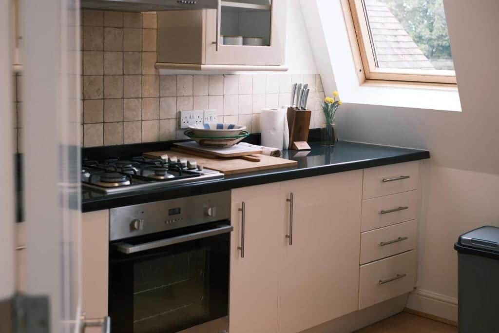 A kitchen with a gas stove, oven, and cabinets. There is a window providing natural light.