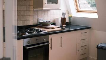 A kitchen with a gas stove, oven, and cabinets. There is a window providing natural light.