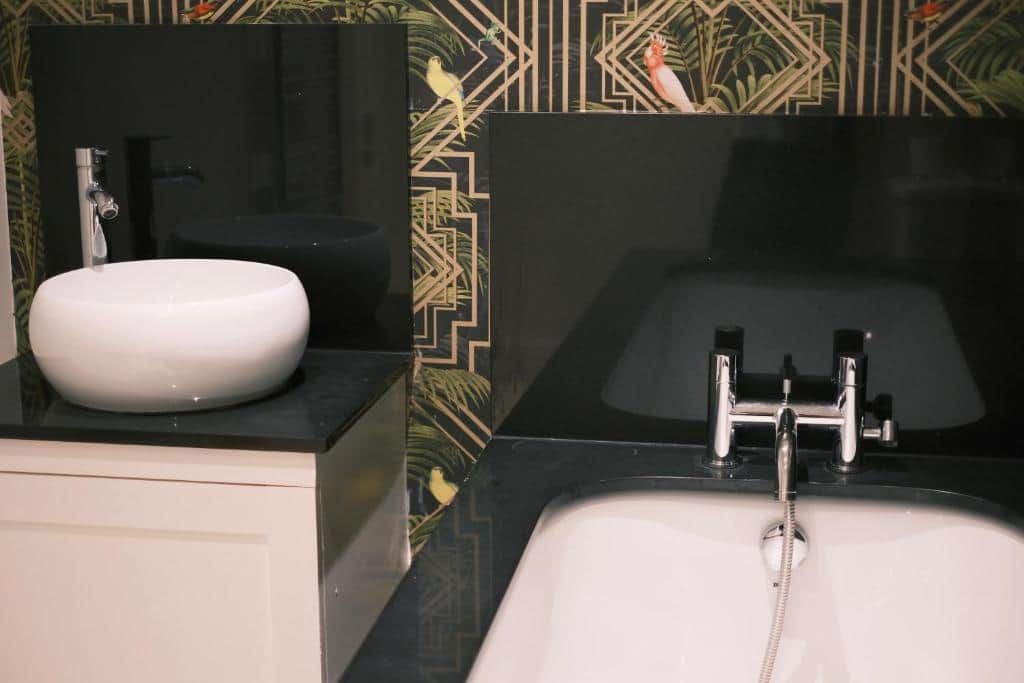 Une salle de bain avec un lavabo blanc, un miroir et un meuble-lavabo noir.