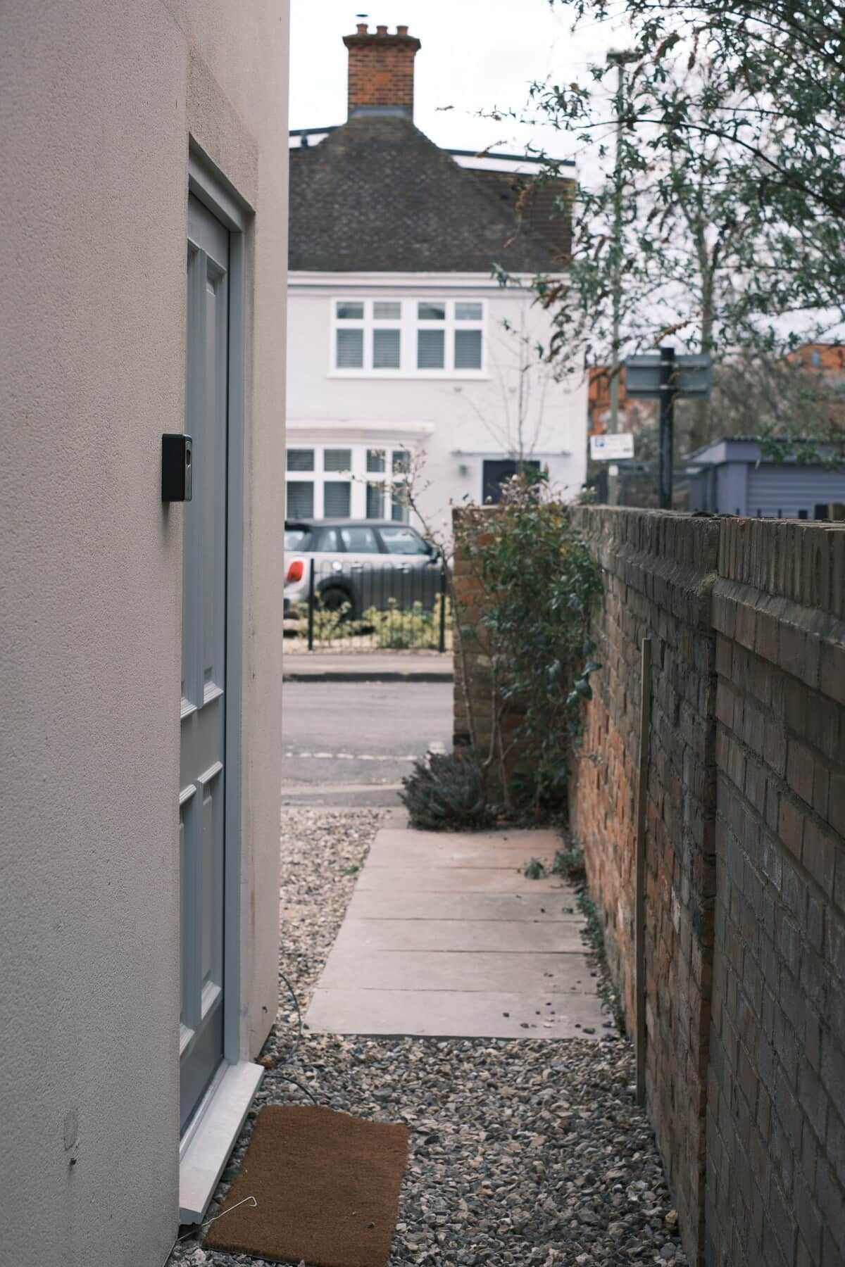A narrow alleyway with a concrete path, a metal gate, and a brick wall.