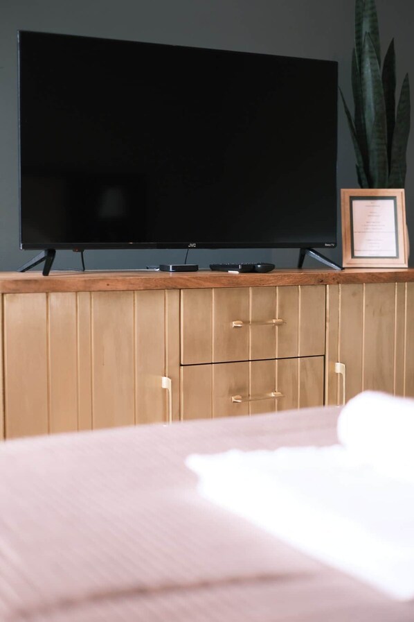 Un téléviseur posé sur un meuble en bois, avec une télécommande et un certificat encadré.