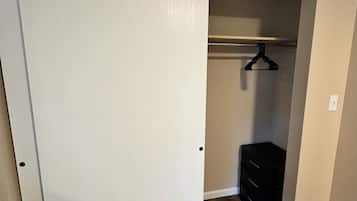 A room with a closed closet, a wooden floor, and a black dresser.