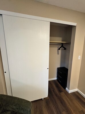 Ein Zimmer mit geschlossenem Kleiderschrank, Holzboden und einem schwarzen Schminktisch.